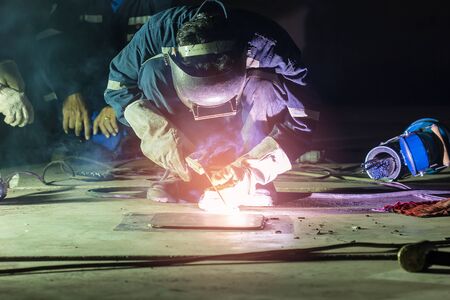 Male  worker wearing protective clothing repair  bottom plate storage tank industrial construction...