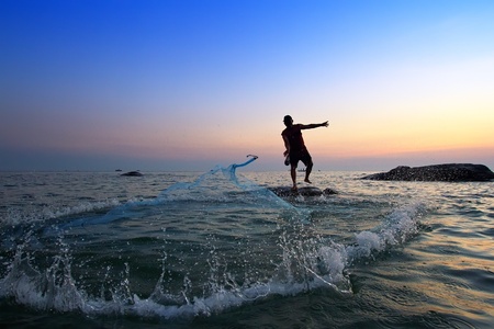 throwing fishing net during sunrise, Thailand