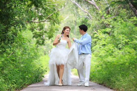happy bride and groom walking in the green forestの写真素材