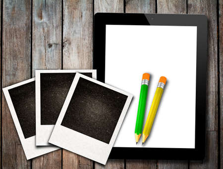Teblet pc with pencil  and old paper photo frame on wood table