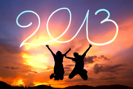 happy new year 2013. young couple  jumping happy 2013 by flashlight in the air on the beach before sunriseの写真素材