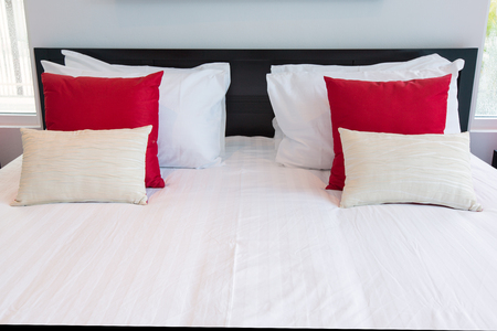 White and red pillows on a bed Comfortable soft pillows on the bedの写真素材