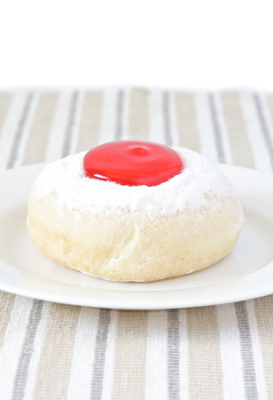 Donut with strawberry jam on white dish.の写真素材