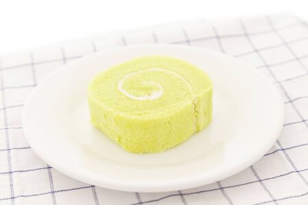 Green tea swiss roll cake on white dish.の写真素材