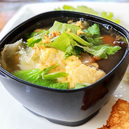 Egg drop soup in black bowl.の写真素材