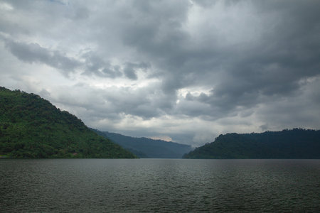 Rainy season clouds in the reservoir behind are mountains.の写真素材
