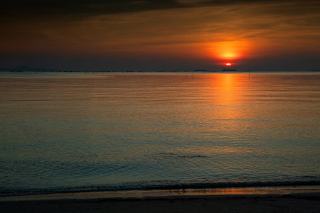 Sunrise/sunset at sea, calm waves and orange sky.の写真素材