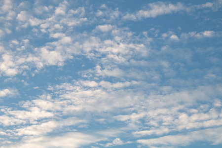 The blue sky was dotted with small fluffy white cloudsの写真素材