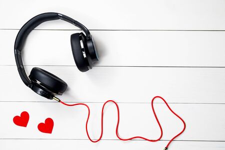 Black headphone and Red cable isolate on wood white table background,の写真素材