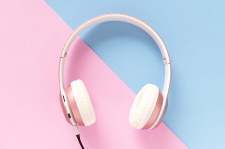 Pink headphone and black cable on pastel color blue and pink background. Music concept.の写真素材