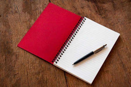 Red notebook and pen on wooden table texture background, Concept for Learning, With copy space for add text message.の写真素材