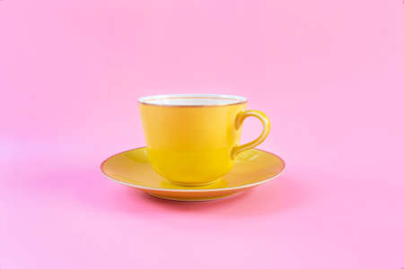 Empty yellow cup on pink pastel color background. Yellow mug empty blank for coffee or tea. concept relaxの写真素材