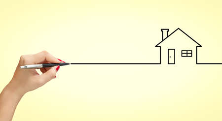 Woman hand Drawing dream picture. Dream house on pastel yellow background. Concept dream drawing to have a woman's houseの写真素材