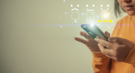 Customer review satisfaction feedback survey concept, Using hand holding Smartphone and touching to tick sign on virtual smiley face for client evaluation product and service best qualityの写真素材