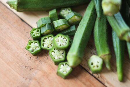 Farm fresh raw okra slices on wooden rustic aged chopping board. Close up of Lady Fingers or Okra over wooden background.の写真素材