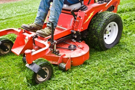 Man on a riding lawn mower that has grass stuck to the wheels. Spring and summer outdoor...