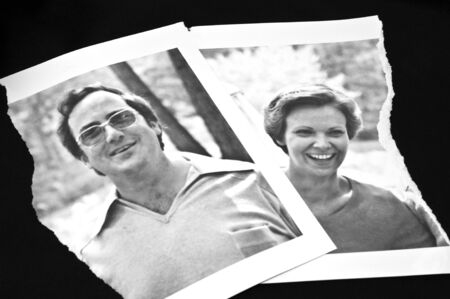 An old black and white photograph of two people in happy times torn in half as a metaphor or concept for break-up, divorce, split, etc.の写真素材