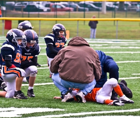 Forsyth County, Cumming GA - October 17, 1009 - A young player down after a tackle on the field. Opposing team looking on. He wasn't hurt badly.A team of 7-8-9 year old boys during a game of the recreation department little league football program duringのeditorial素材