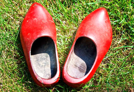 A pair of old, red, wooden shoes in the grass.の写真素材