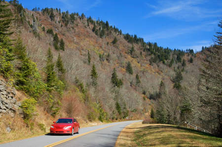 A single car on a stretch of mountain highway in early winter.の写真素材