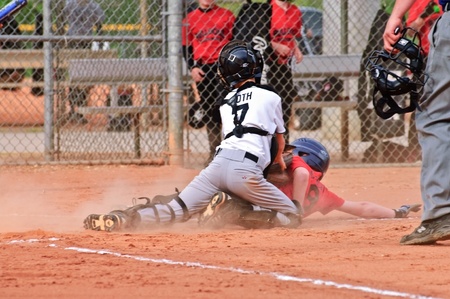 Cumming, GA, USA - April 19, 2010 - A little league baseball catcher tagging the runner out on homeplate at a game in Forsyth County, Cumming GA, 4-10-2010.  A regular season game between the Bulldogs and the Raiders.のeditorial素材