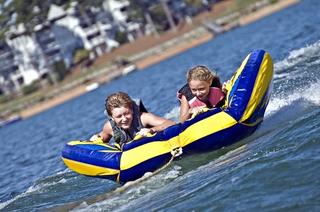 Young boy and girl on a tube behind a boat.の写真素材