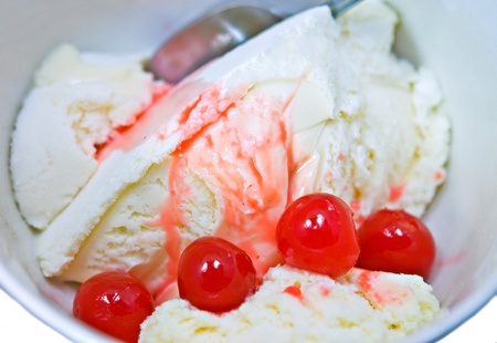A bowl of vanilla frozen yogurt or ice cream with cherries on top.の写真素材