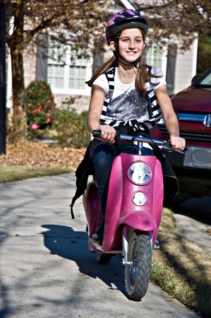 A preteen girl having fun riding an electric scooter.の写真素材