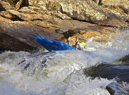 Kayaker fighting to stay afloat in the rapids section of a swiftly flowing river  の写真素材