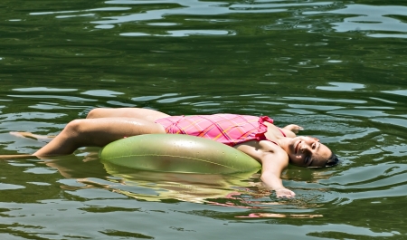 A young girl relaxing on a float in the water の写真素材