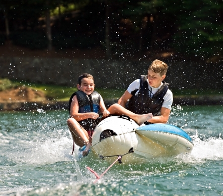 Children on a float behind a boat trying not to fall off 
