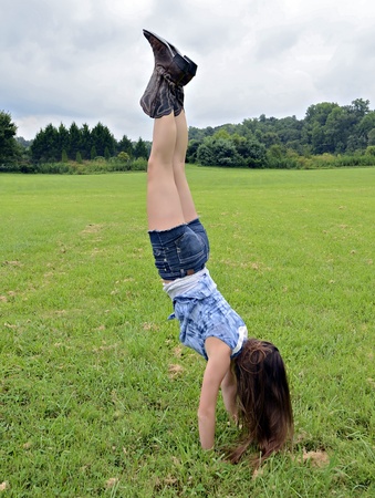 A teenage girl doing a handstand outdoors.