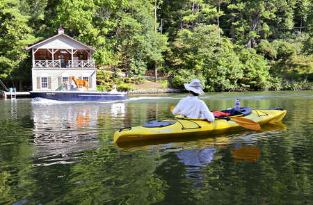 LAKE RABUN  GA  USA-AUGUST 25  People enjoying a day on a lake, August 25, 2013   A woman kayaking and a family riding in a boat with their dog   Fun ideas for vacations or holidays のeditorial素材