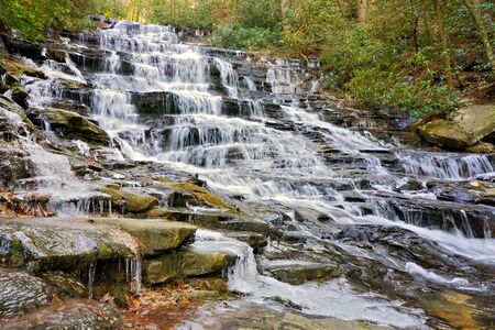 waterfall flowing over rocks on a hiking trail.