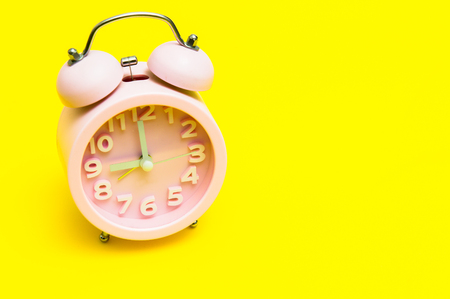 Pink alarm clock on yellow backgroundの写真素材