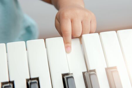 The hand of a girl pressing a musical keyboard.の写真素材