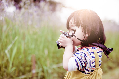 Little Asian girl is taking a photo.