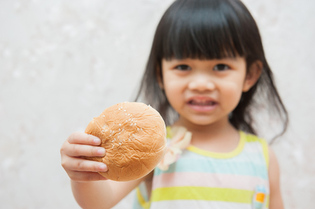 Cute little girl eating buns, delicious bread.の写真素材