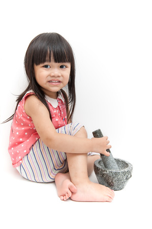Lovely girl is pounding stone mortar with white background.の写真素材