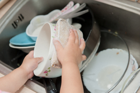 Little children are washing dishes.の写真素材