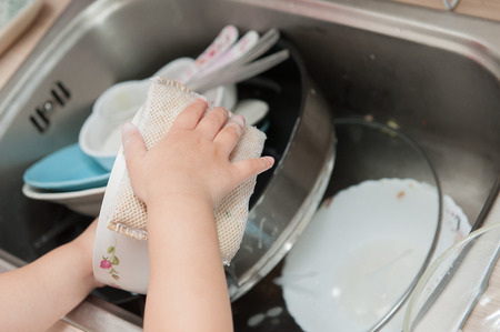 Little children are washing dishes.の写真素材