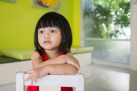 Asian little girl, sitting on a chairの写真素材