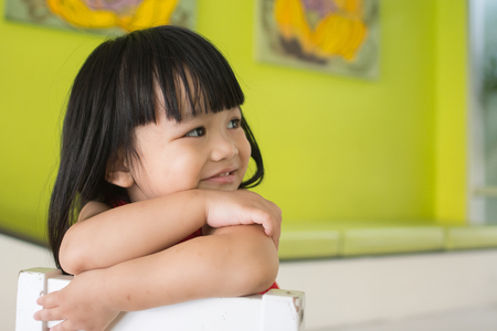 Asian little girl, sitting on a chairの写真素材