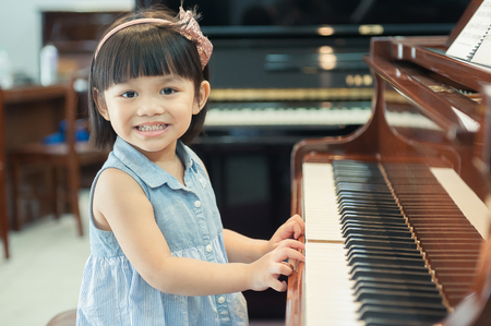 The cute little girl play piano With Grand Piano.の写真素材