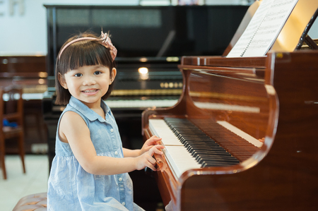 The cute little girl play piano With Grand Piano.の写真素材