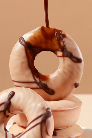 Donuts with chocolate and caramel on a beige background, close-upの写真素材