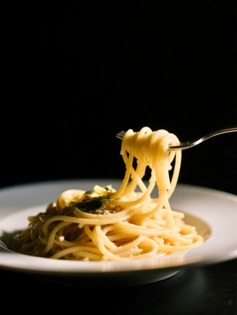 Spaghetti with pesto sauce on a white plate and black backgroundの写真素材