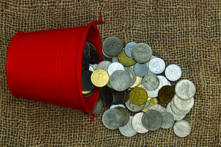 bucket drop and spill out coins over sackcloth with dramatic lighting setupの写真素材
