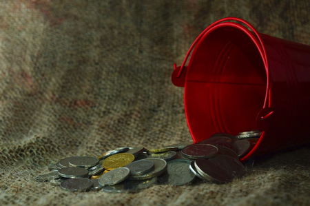 bucket drop and spill out coins over sackcloth with dramatic lighting setupの写真素材