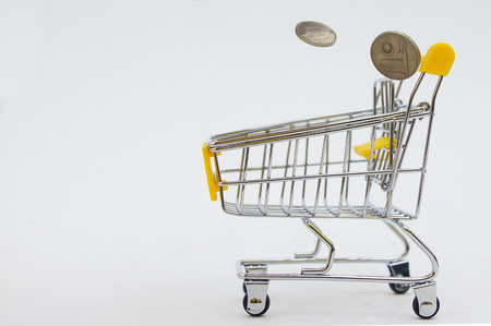 coins drops into shopping cart over white backgroundの写真素材